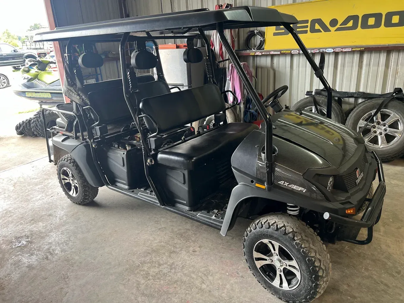Black off-road golf cart with roof and oversized tires parked in a garage
