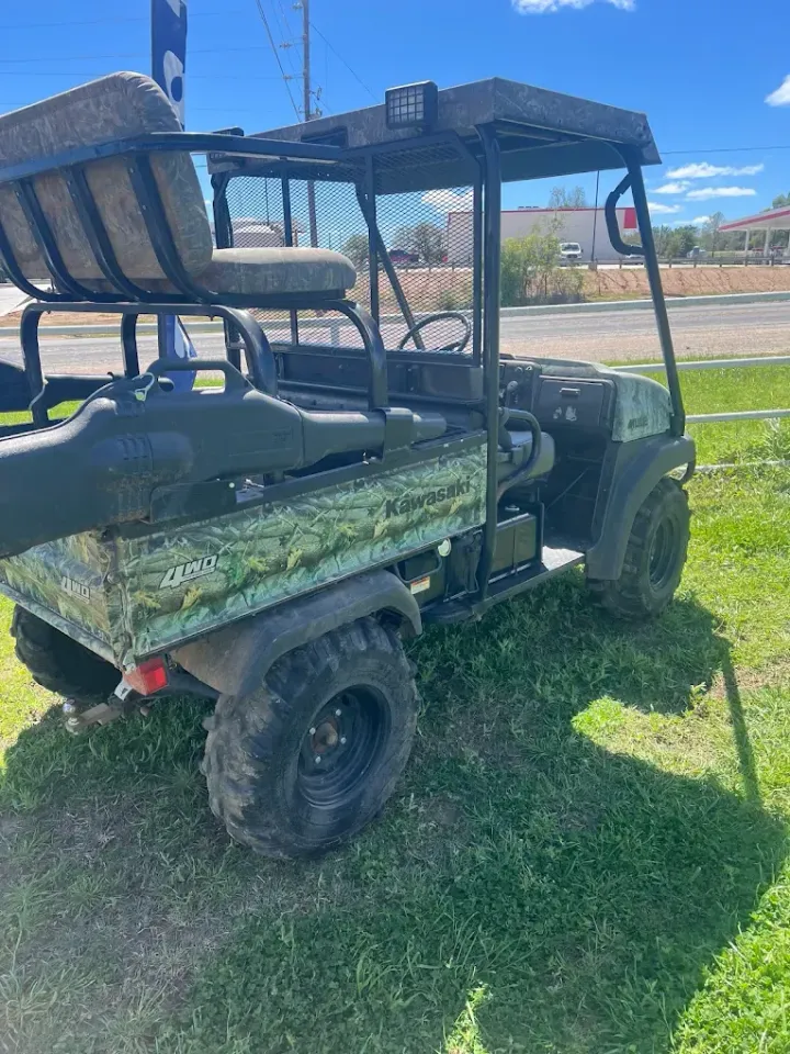 Camouflaged off-road utility vehicle parked on grass under a blue sky