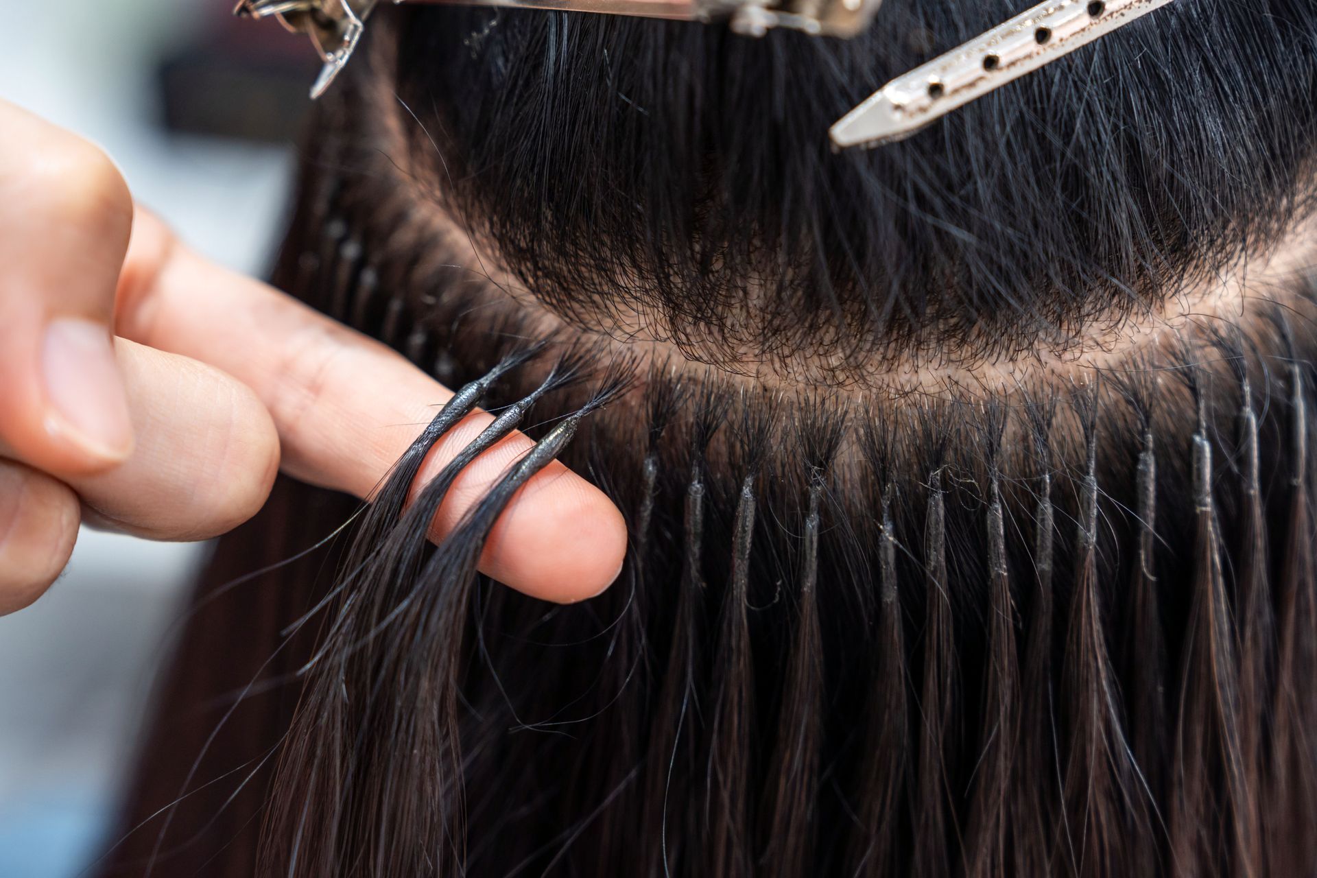 Hair extensions being attached along a scalp part with a small comb and tool Hair extensions being attached along a scalp part with a small comb and tool