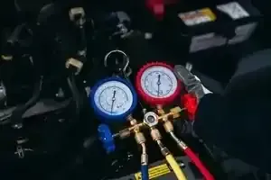 Blue and red gauges connected to hoses on HVAC service equipment