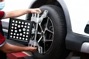 Technician aligning a car wheel with a computerized wheel alignment machine
