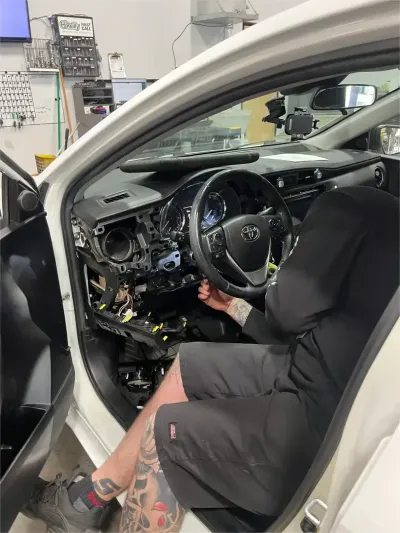 Gloved hands using a diagnostic tool on a car engine in a workshop