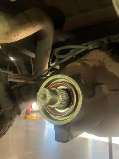 Hands repairing a metal automotive clutch assembly on a workshop floor with tools scattered around.
