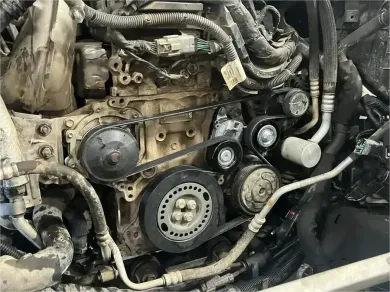 Open car engine bay with visible belts, hoses, and metal components under the hood