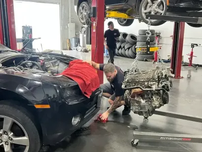 Mechanic adjusting engine components inside a car bay