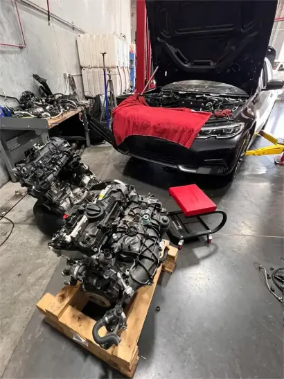 Mechanic working on a car engine with the valve cover removed, inspecting the exposed camshaft.