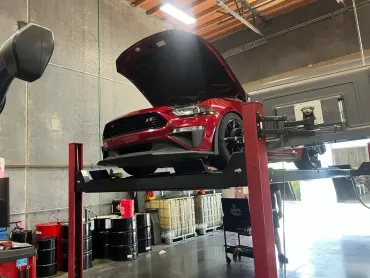 Mechanic in blue coveralls changing a car tire on a wheel balancer