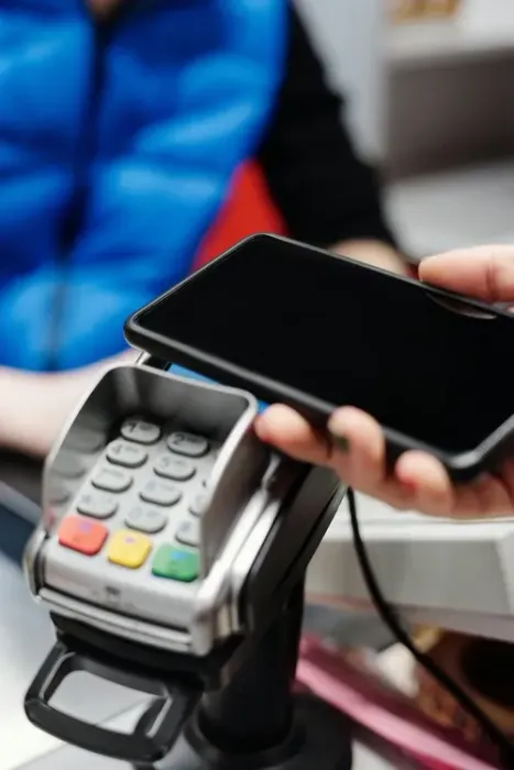 Contactless payment at a card reader with a smartphone near a checkout terminal