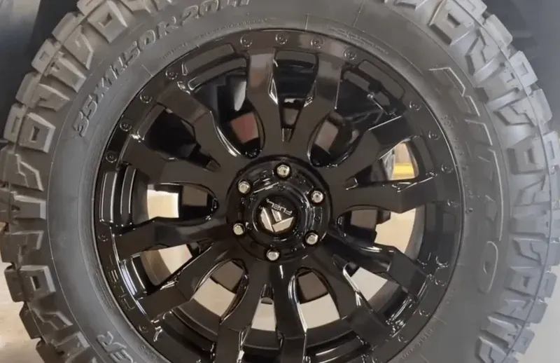 A black, multi-spoke Fuel off-road wheel with a rugged, deep-tread tire mounted on a vehicle.