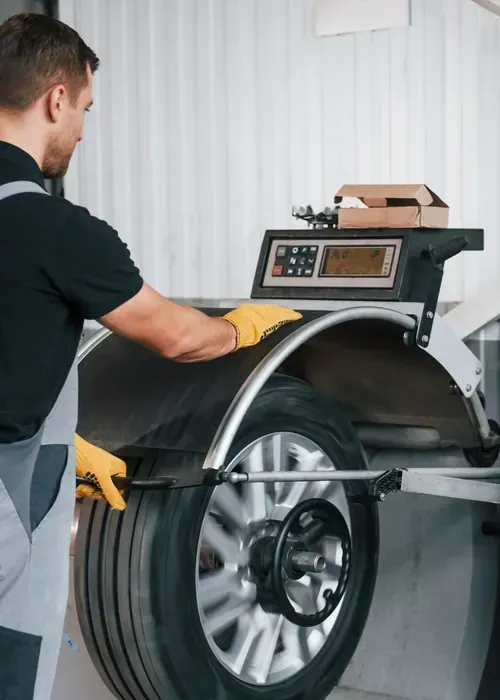 Technician measuring a tire on a balancing machine in a workshop