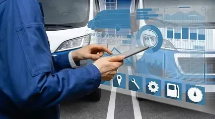 Technician in blue jacket using a tablet beside a car with a digital vehicle diagnostics interface overlay