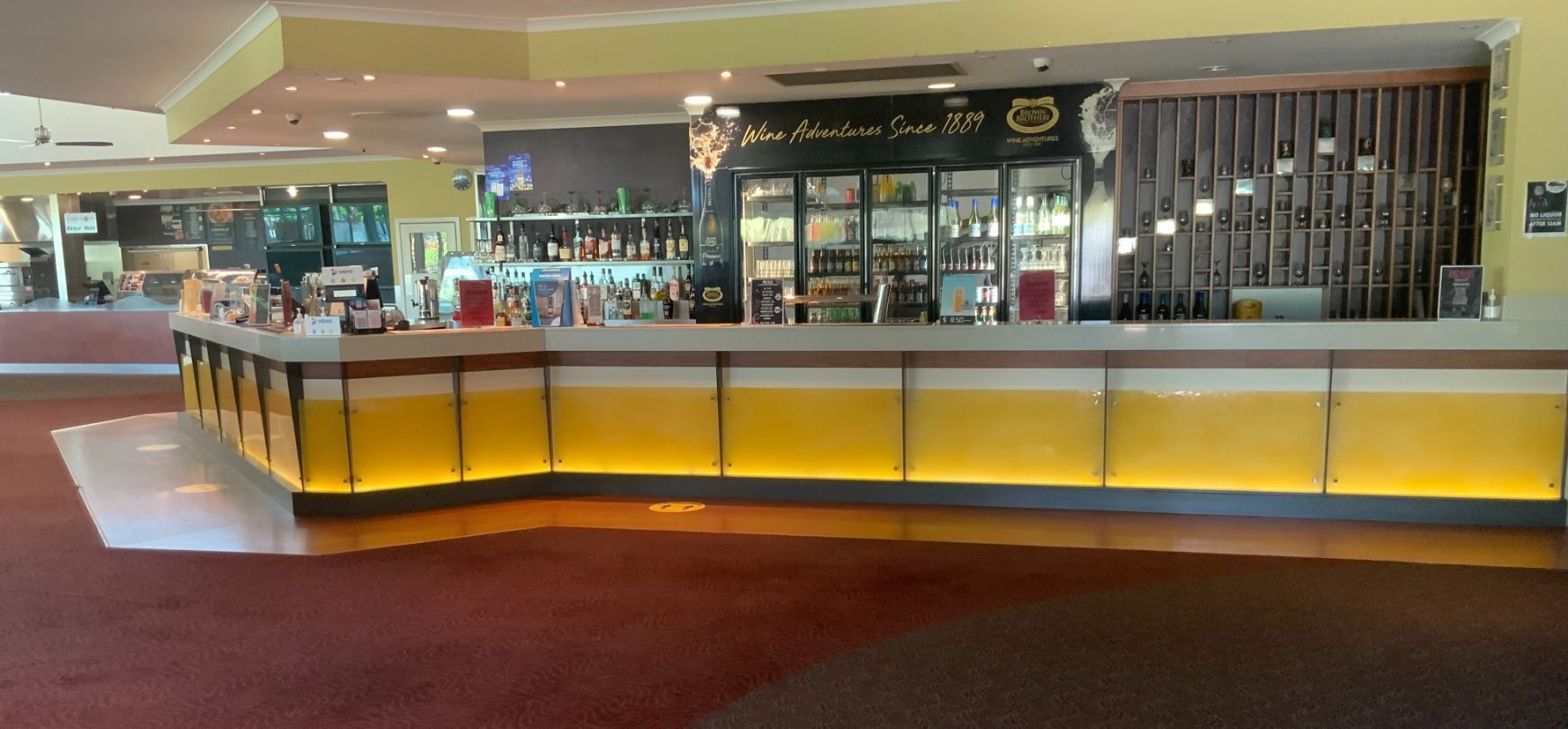 Bar With Yellow-lit Facade and Drinks Behind the Counter — Capricorn Tavern in Taranganba, QLD