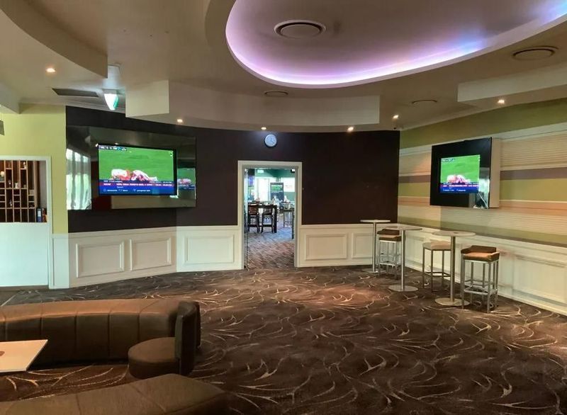 Interior of a Sports Bar With Tvs, Seating, and a View Into Another Room — Capricorn Tavern in Taranganba, QLD
