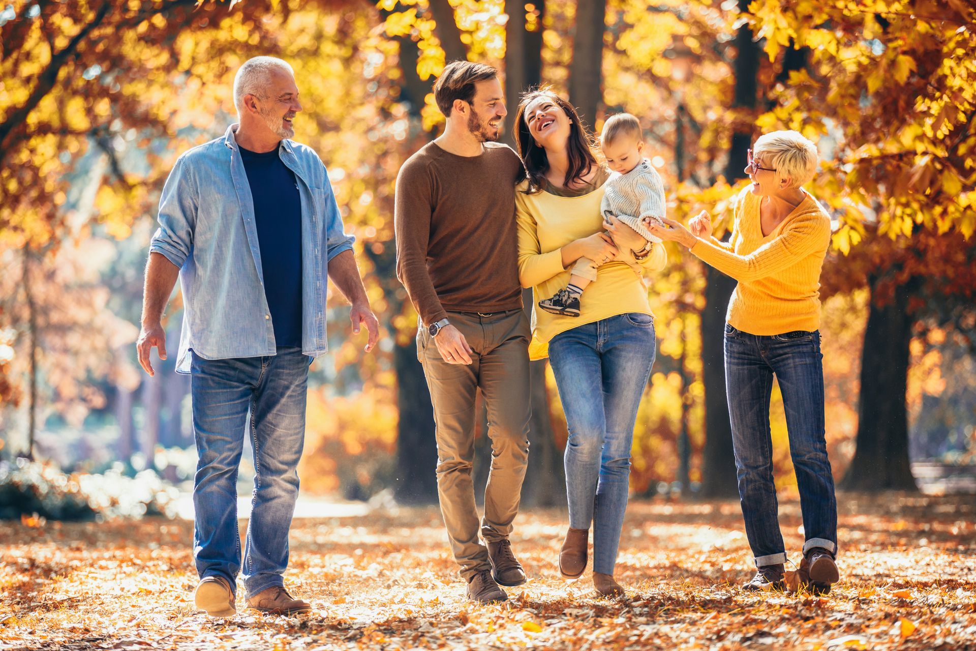 A family is walking through a park in autumn.