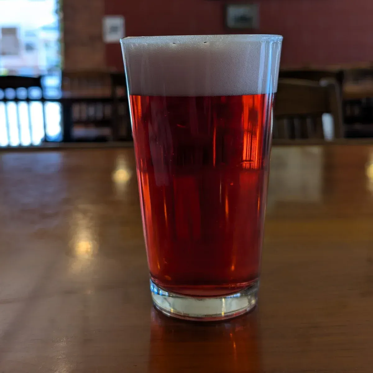 A glass of red drink on a wooden table in a café