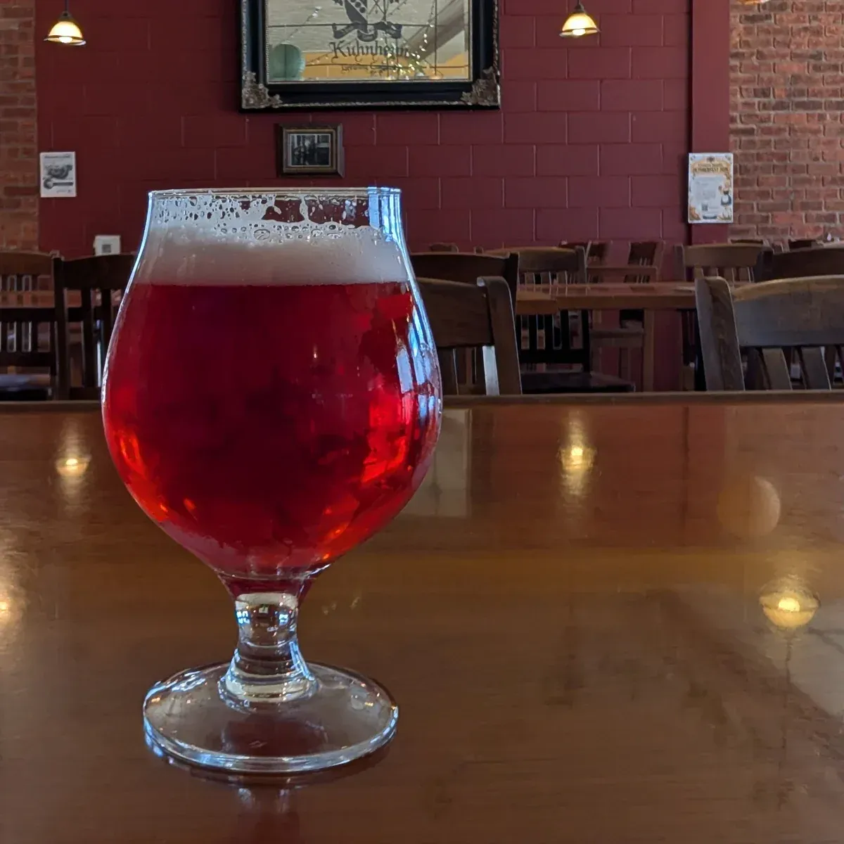 Red beer in a stemmed glass on a wooden table in a dimly lit bar