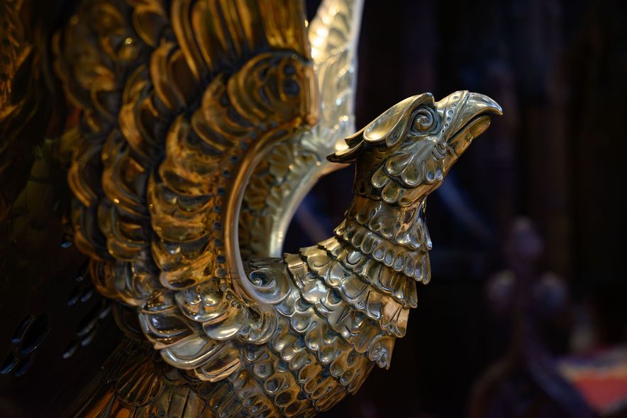 Gold ornate bird sculpture with detailed feathers against a dark background