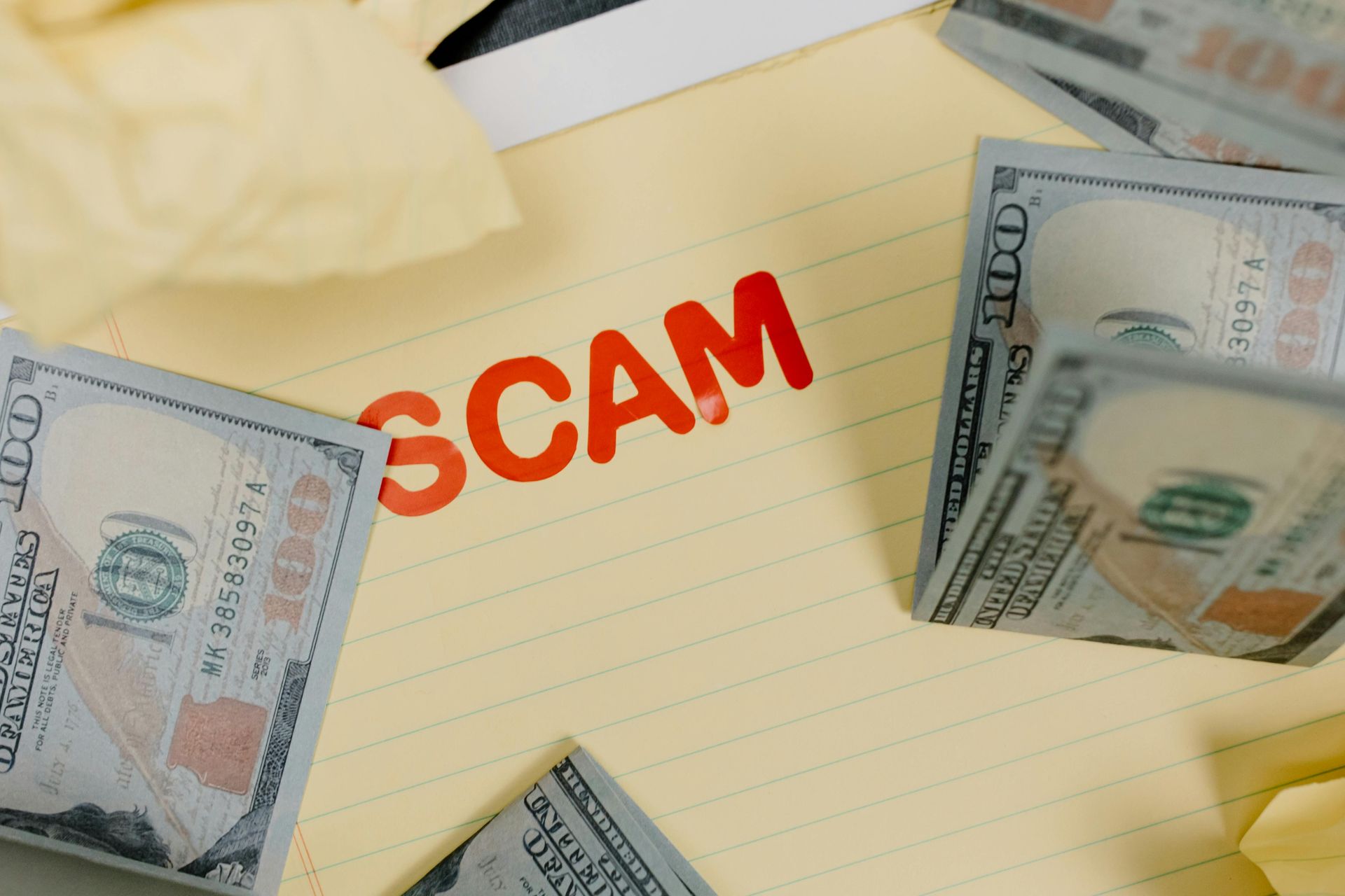 “SCAM” stamped on paper with dollar bills and tissues