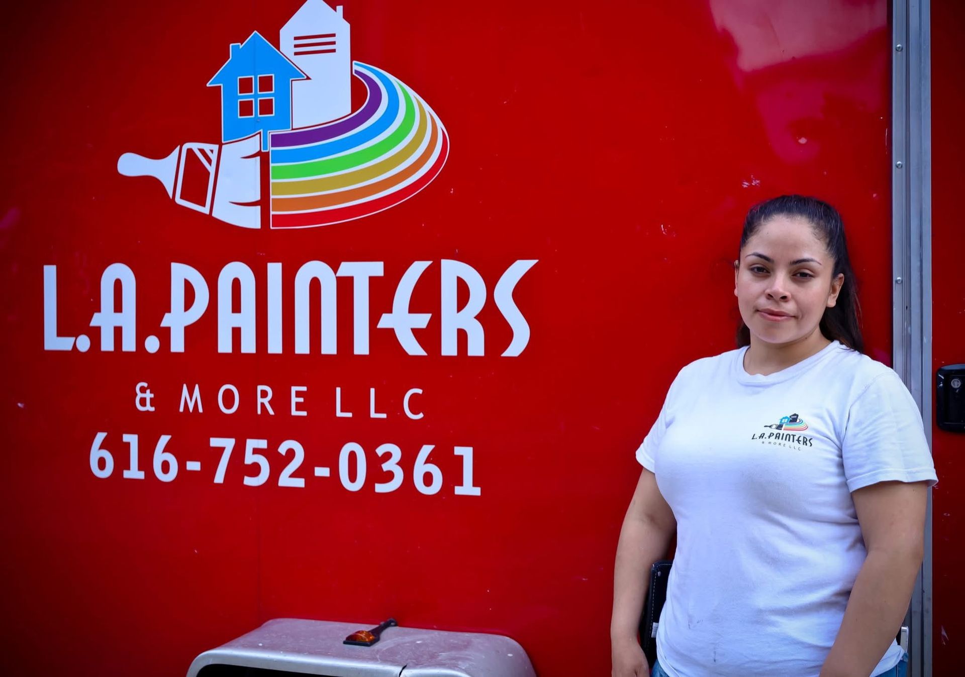 L.A. Painters sign on red wall with woman standing beside it and phone number 616-752-0361