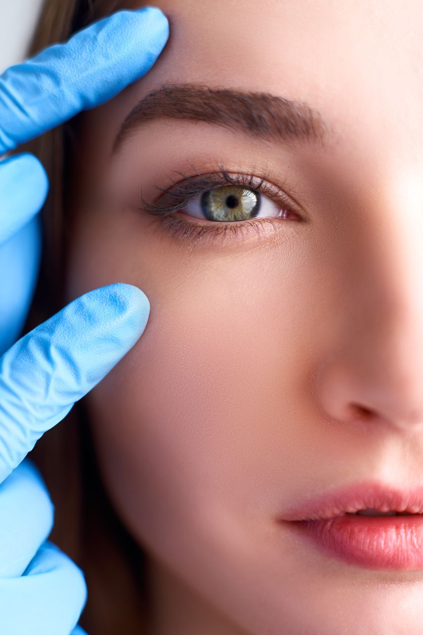 Primer plano del ojo y la cara de una persona examinada con manos enguantadas.