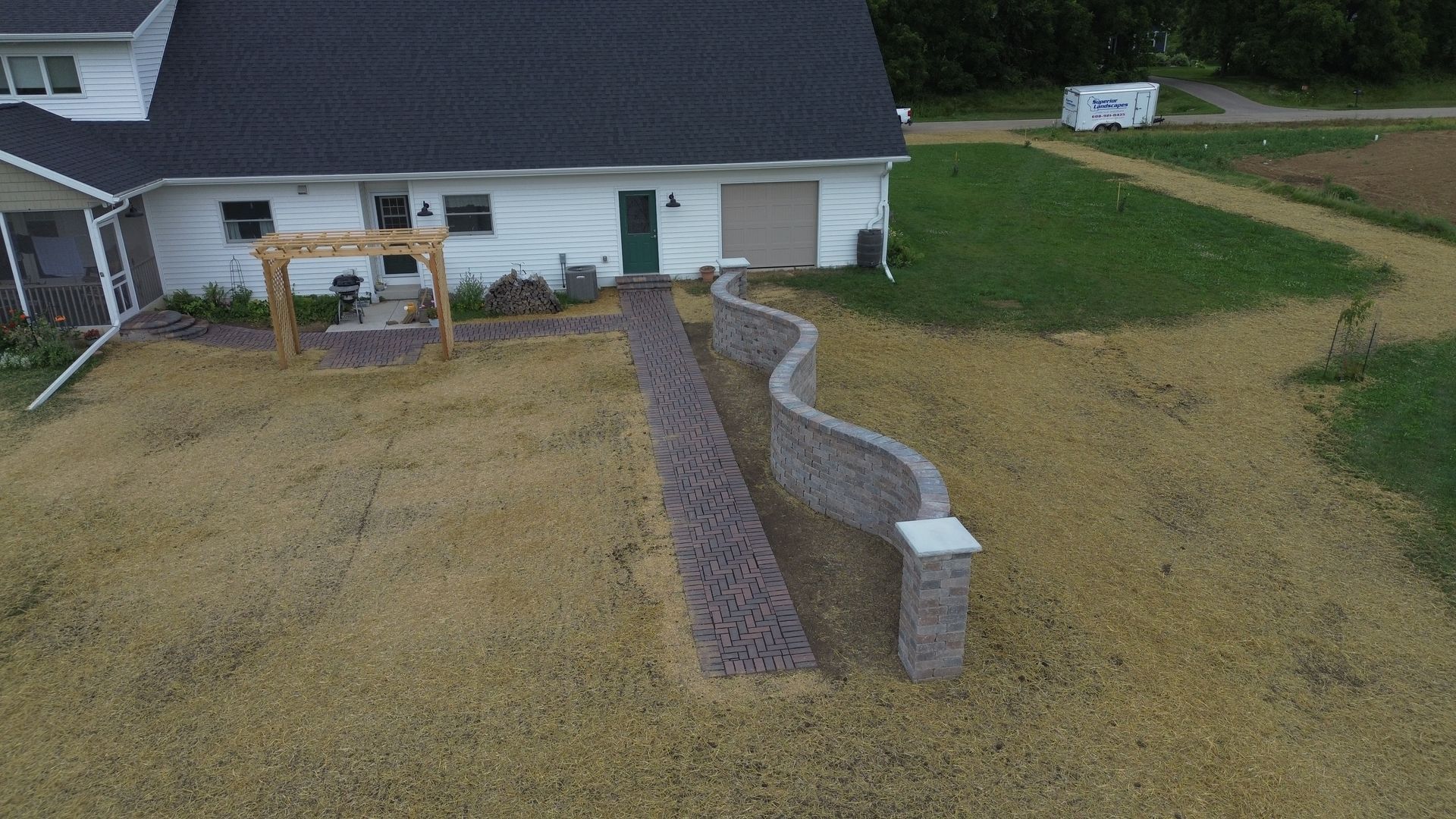 Backyard with a curved gravel drainage bed beside a house and lawn