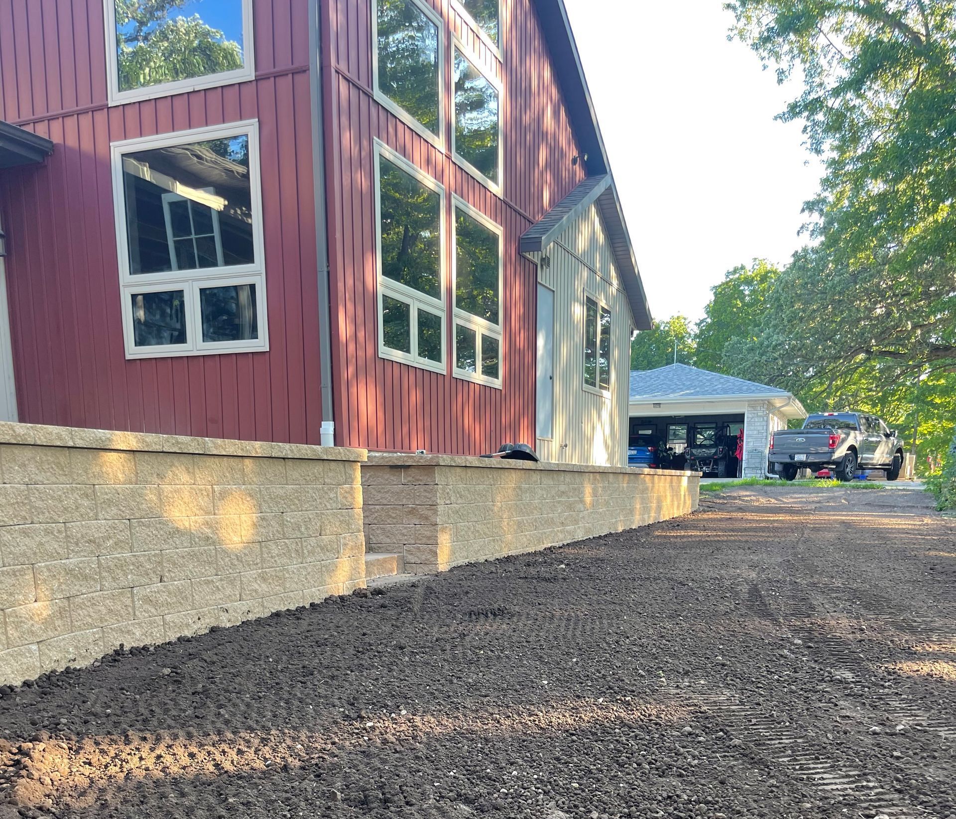 Red building beside a gravel driveway, with trees and a driveway canopy in the background.