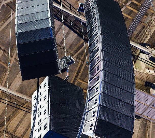 Hanging concert speaker arrays suspended from a venue ceiling, viewed from below