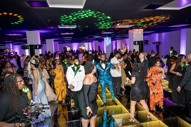 People dancing at a colorful indoor party with bright lights and a crowded dance floor