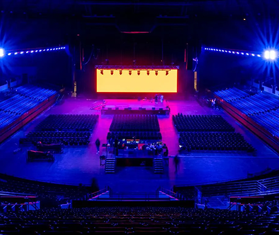 Empty auditorium with blue-purple lighting and a bright yellow stage screen.