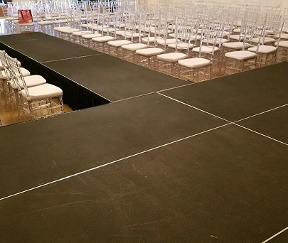 Empty runway-style stage with rows of white chairs arranged around it in a large indoor venue
