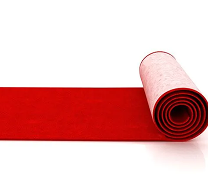 Rolled red carpet on white background, partially unrolled to the left
