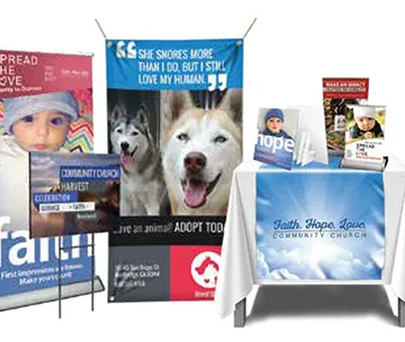 Sample promotional banners and brochures for a church community event, featuring a baby, dog, and table display.