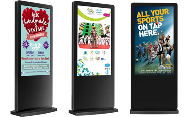 Three digital advertising kiosks with colorful posters on black stands against a white background