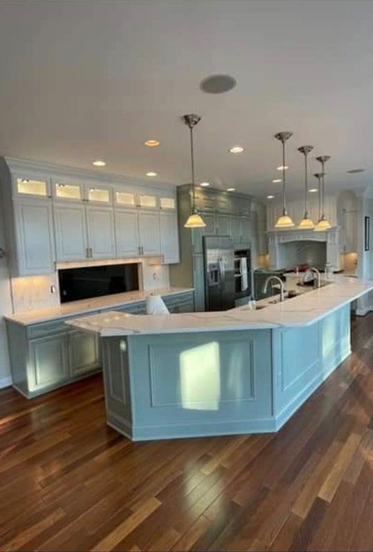 Spacious kitchen with blue island and cabinets, marble countertops, and hardwood floors.