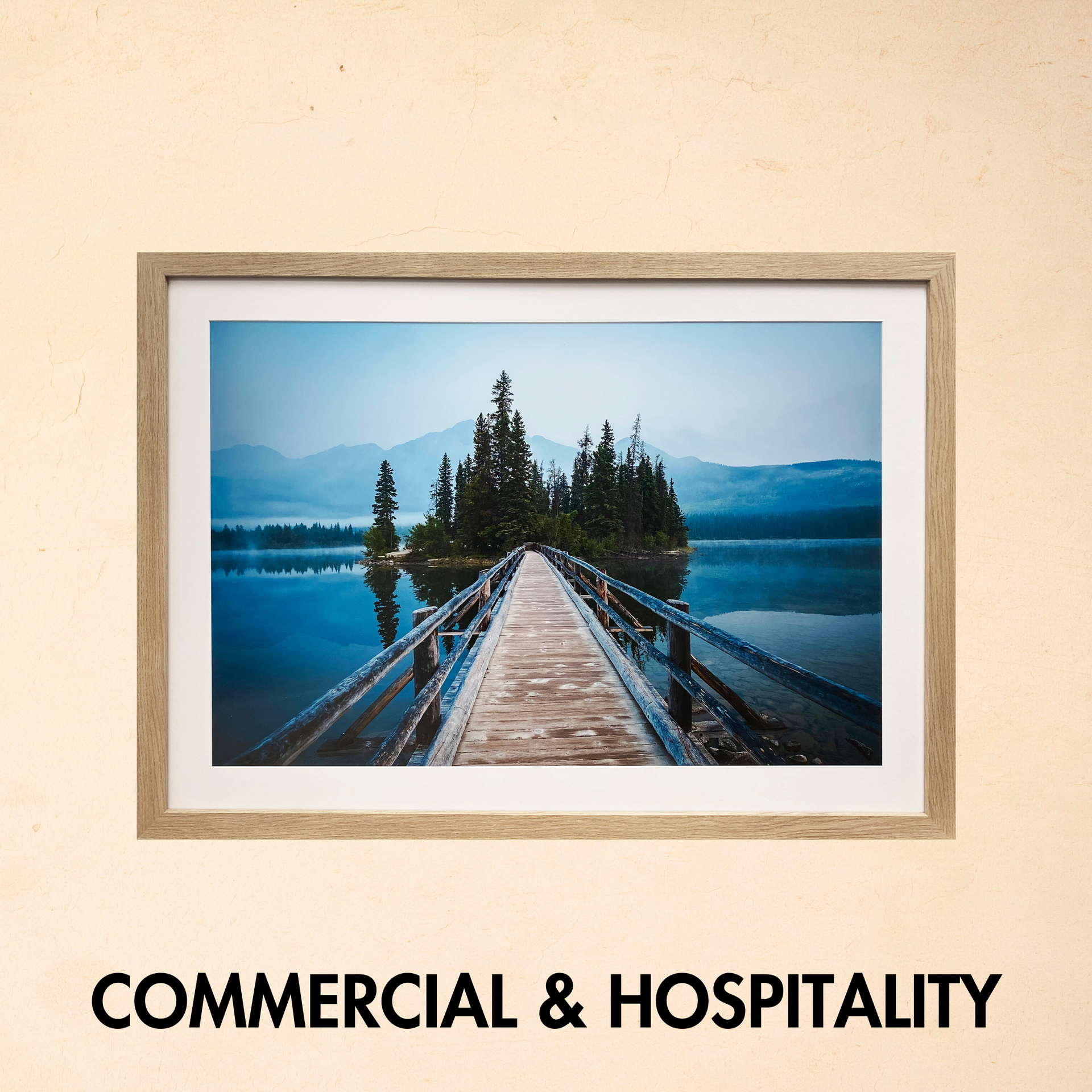Framed photo of a wooden bridge leading to pine trees over a blue lake; “Commercial & Hospitality” text below