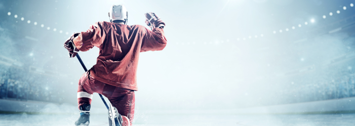 A hockey player is holding a hockey stick on the ice.