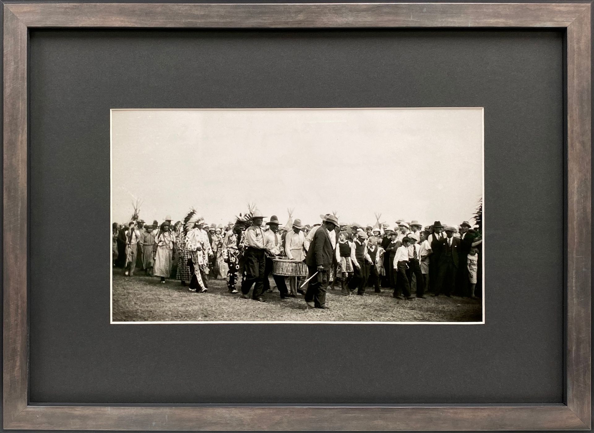 Framed black-and-white photo of a crowd gathered outdoors in a field or open area