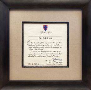 Framed certificate with a cream mat and black frame, featuring a red-and-blue crest and handwritten text.