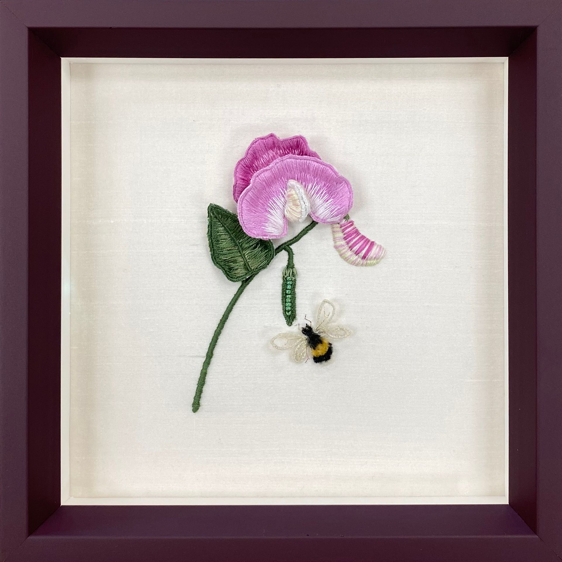 a single pink flower in a shadow box