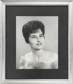 Black-and-white framed studio portrait of a woman in a formal dress with a soft fur wrap