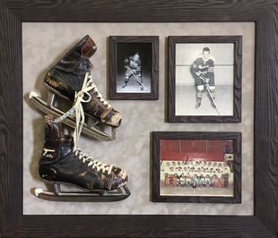 Framed hockey memorabilia with two skates and three black-and-white photos on a gray background
