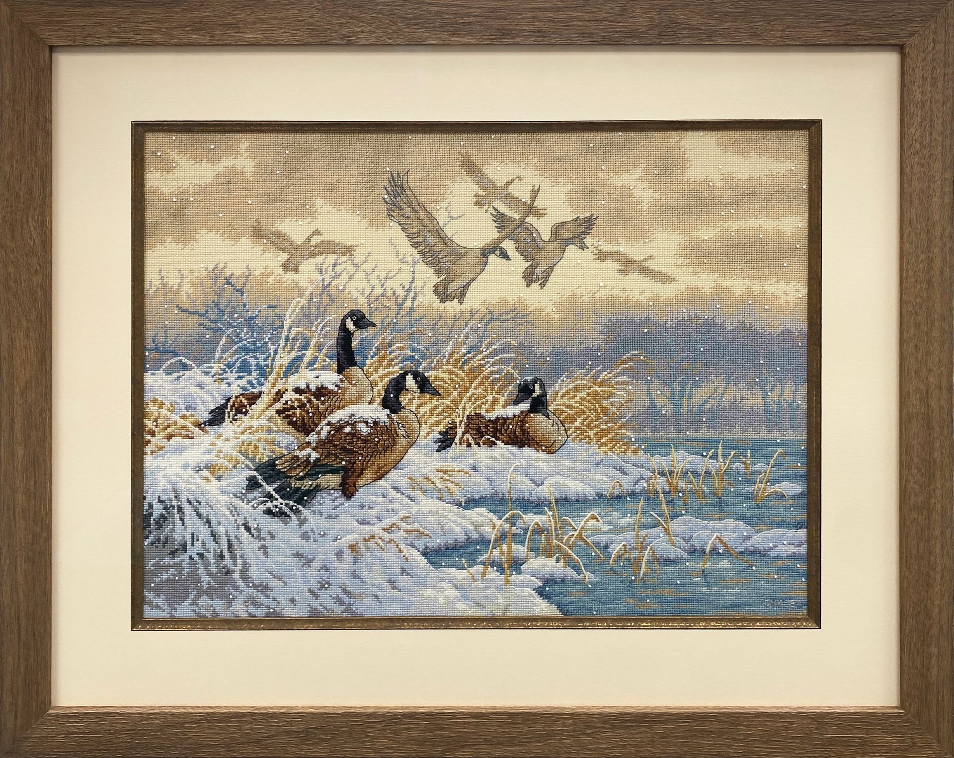 a needlework of three geese framed