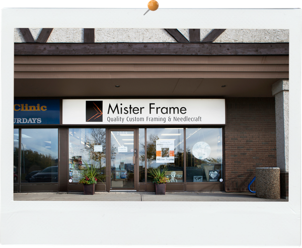 Storefront of Mister Frame with large sign, glass windows, and potted plants outside.