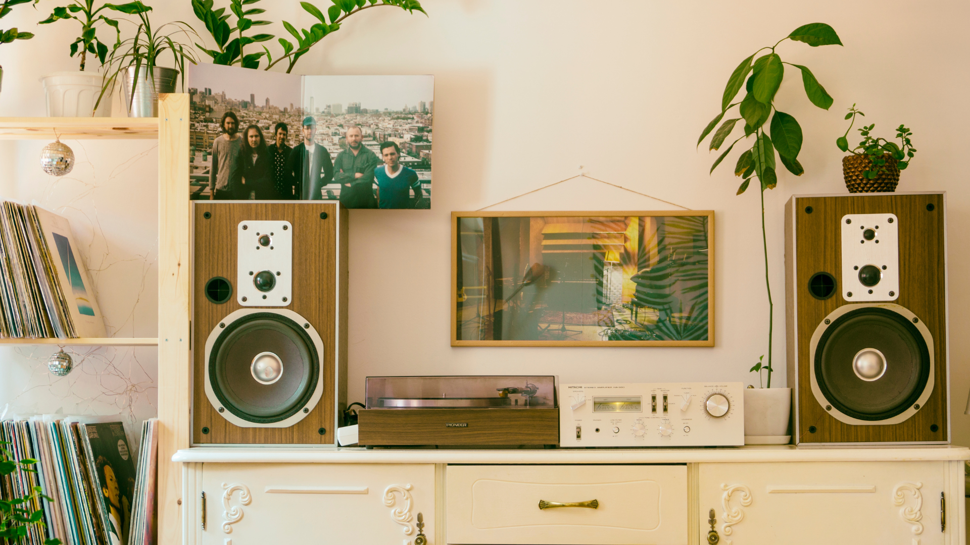 A living room with two speakers, a record player, and a picture on the wall.