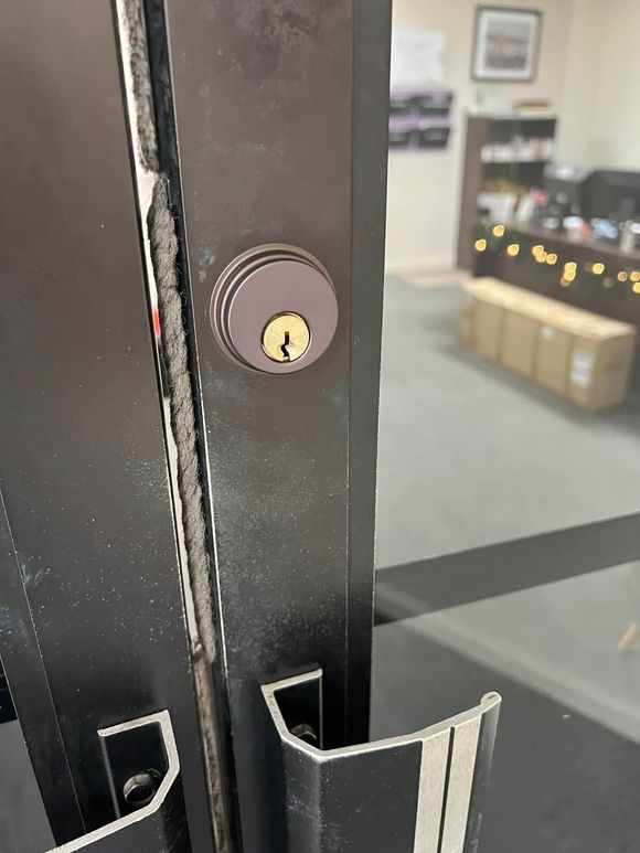 Close-up of a glass door lock and black metal frame in an office lobby