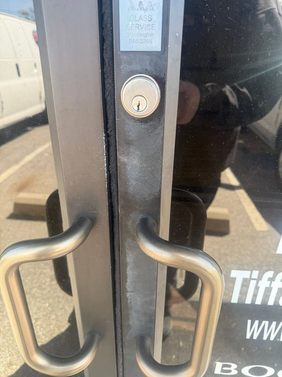 Close-up of black glass double doors with silver handles and a keyhole lock.