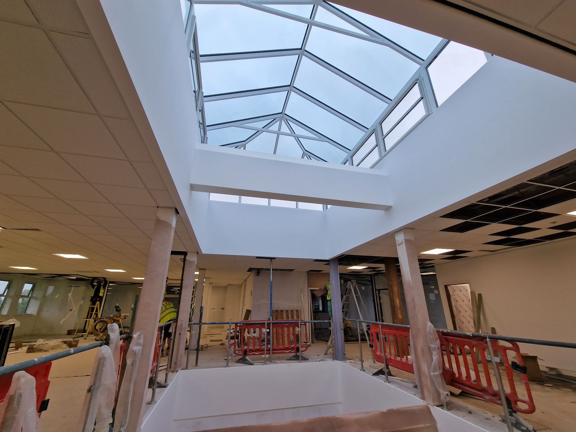 Indoor mall under renovation with skylight, white walls, and orange safety barriers