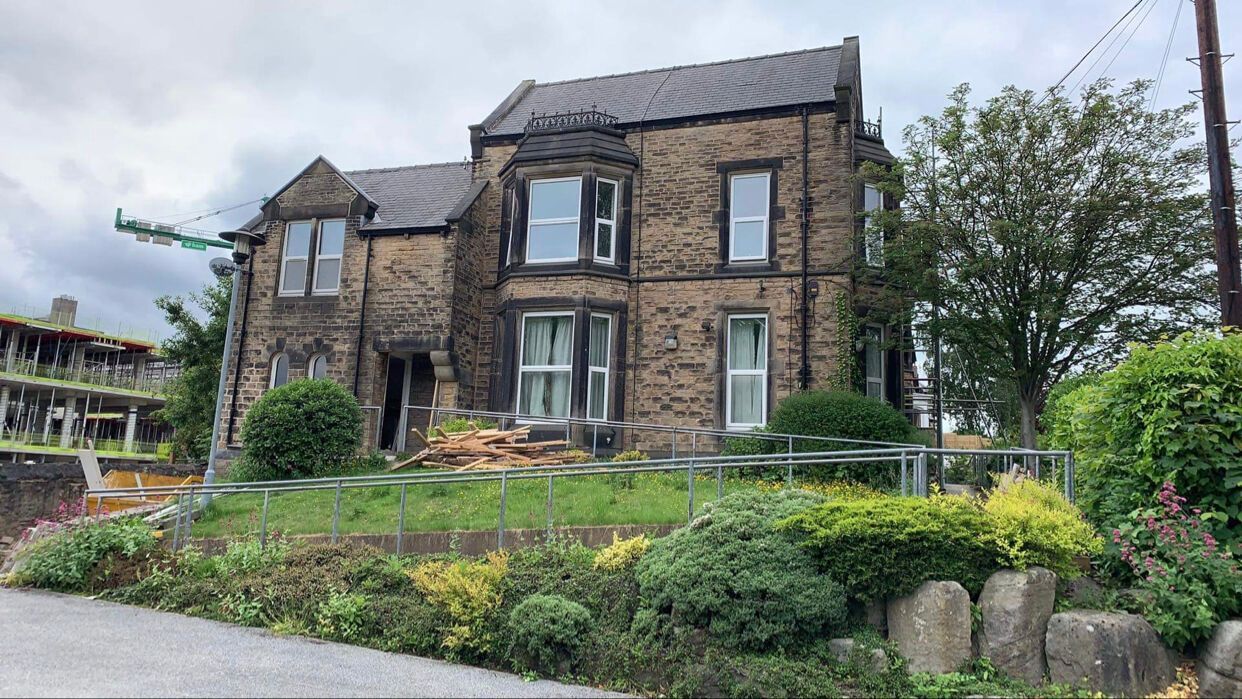 Stone house with bay windows, surrounded by shrubs and flowers in a landscaped garden