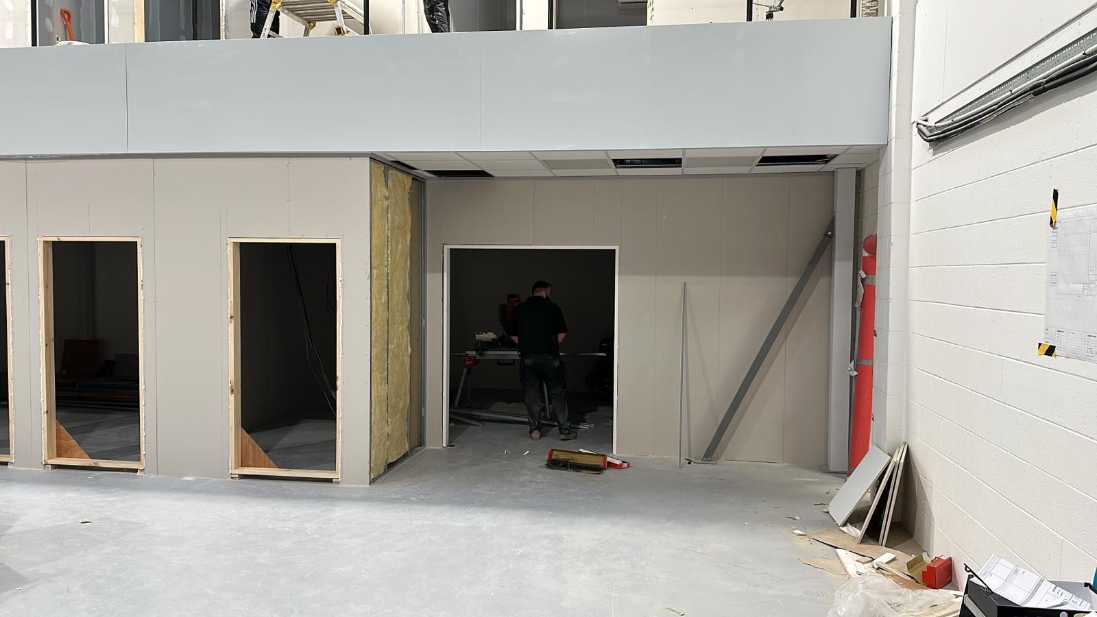 Empty unfinished room with door openings, white walls, and exposed construction materials.