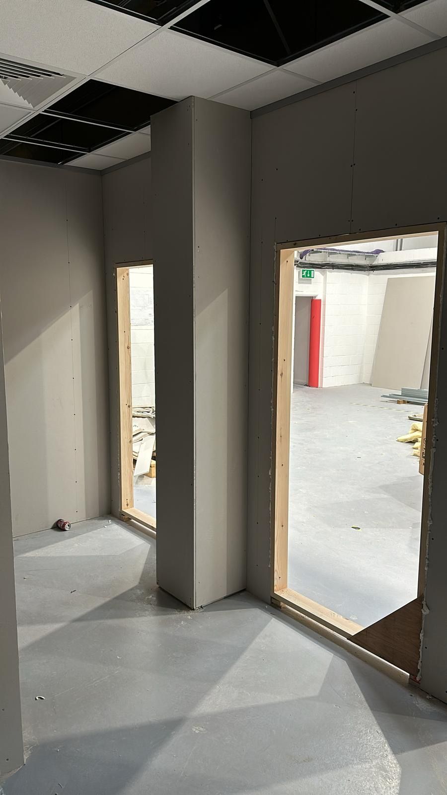 Empty unfinished interior with gray walls, tiled floor, and door openings in a construction site